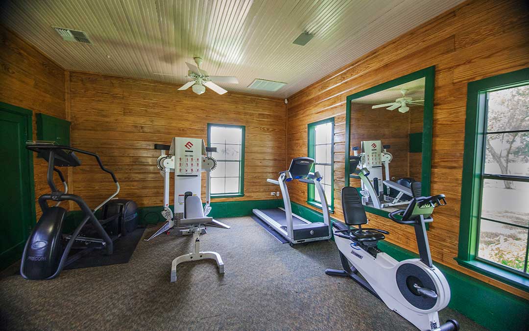 photo of the workout room with a treadmill, elliptical machine, recumbent bike, and weight machine at the Great Oaks Recovery Center - drug addiction treatment - drug rehab near houston, tx