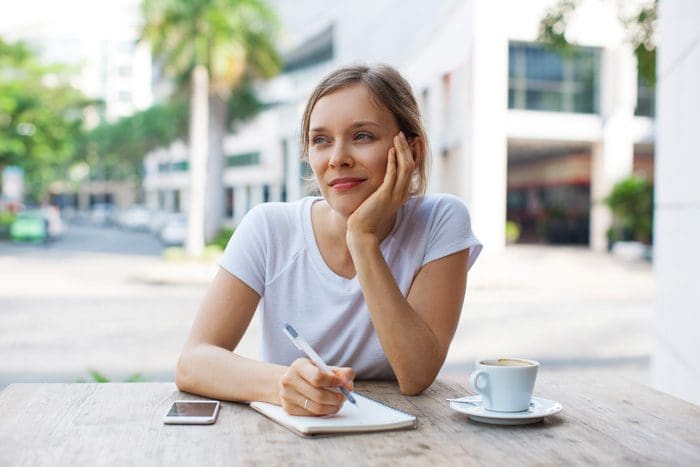 woman at outdoor cafe making a list