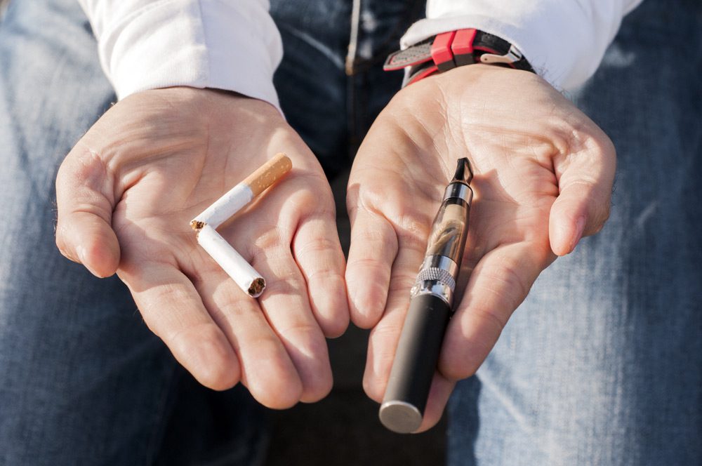 cigarette in one hand and vape pen in the other