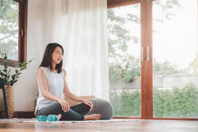 woman sitting on a yoga mat doing breathing or meditation